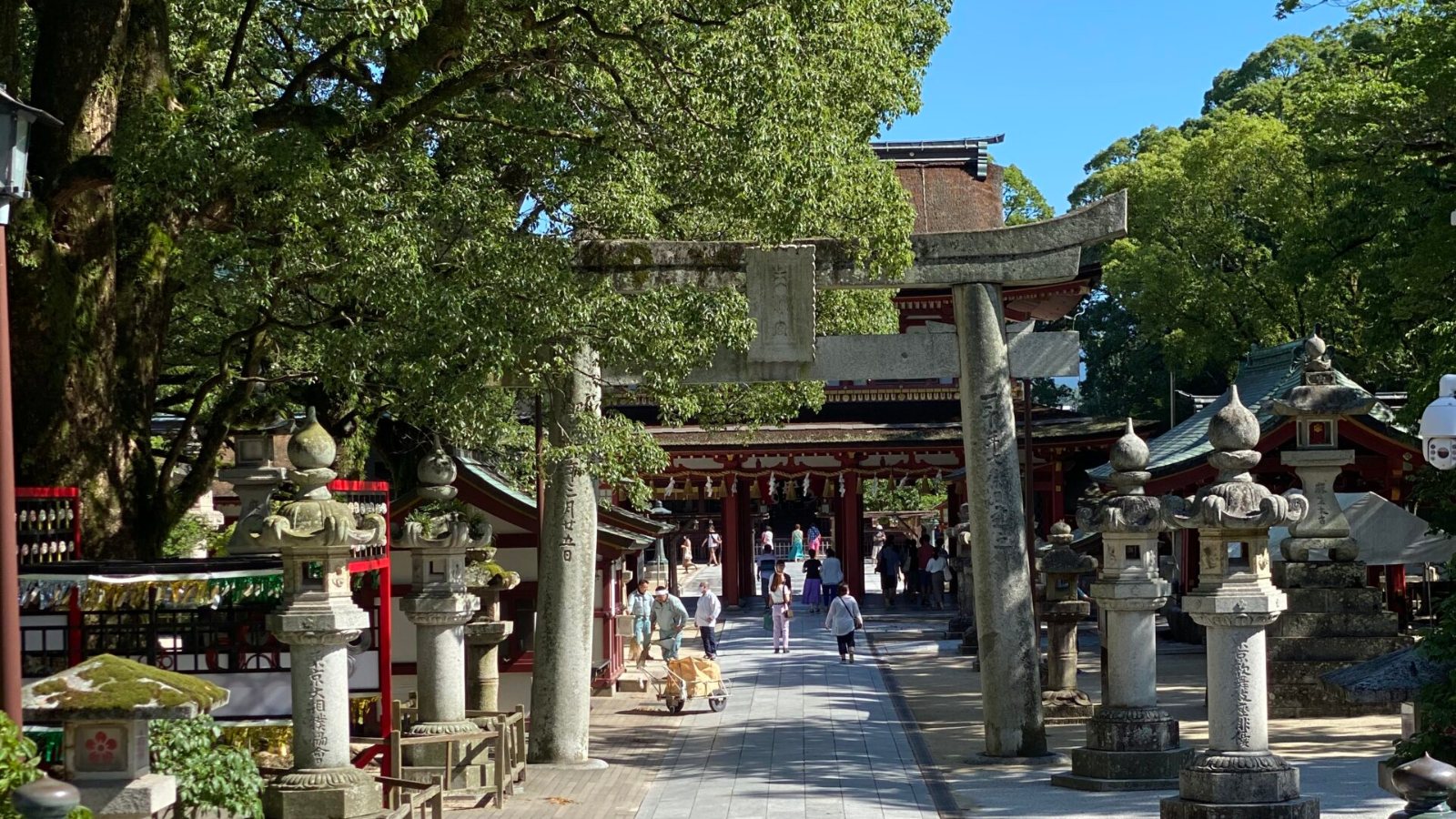 Stone lanterns and a stone torii on the tree shaded approach to the Romon gate at Dazaifu Tenmangu